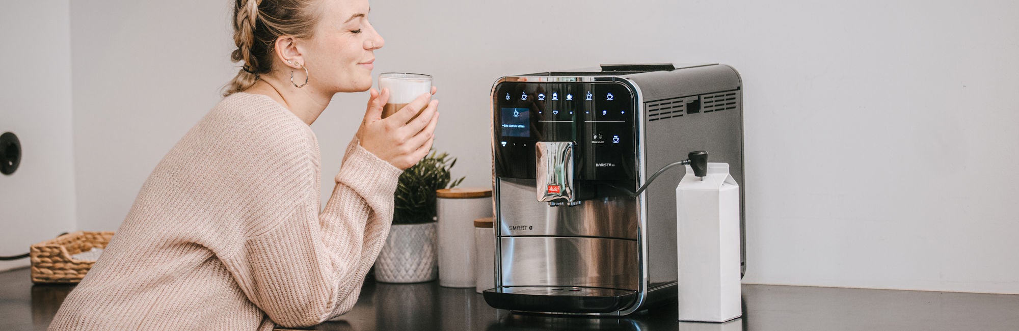 Melitta® FAM Barista Woman with coffee in hand infront of FAM